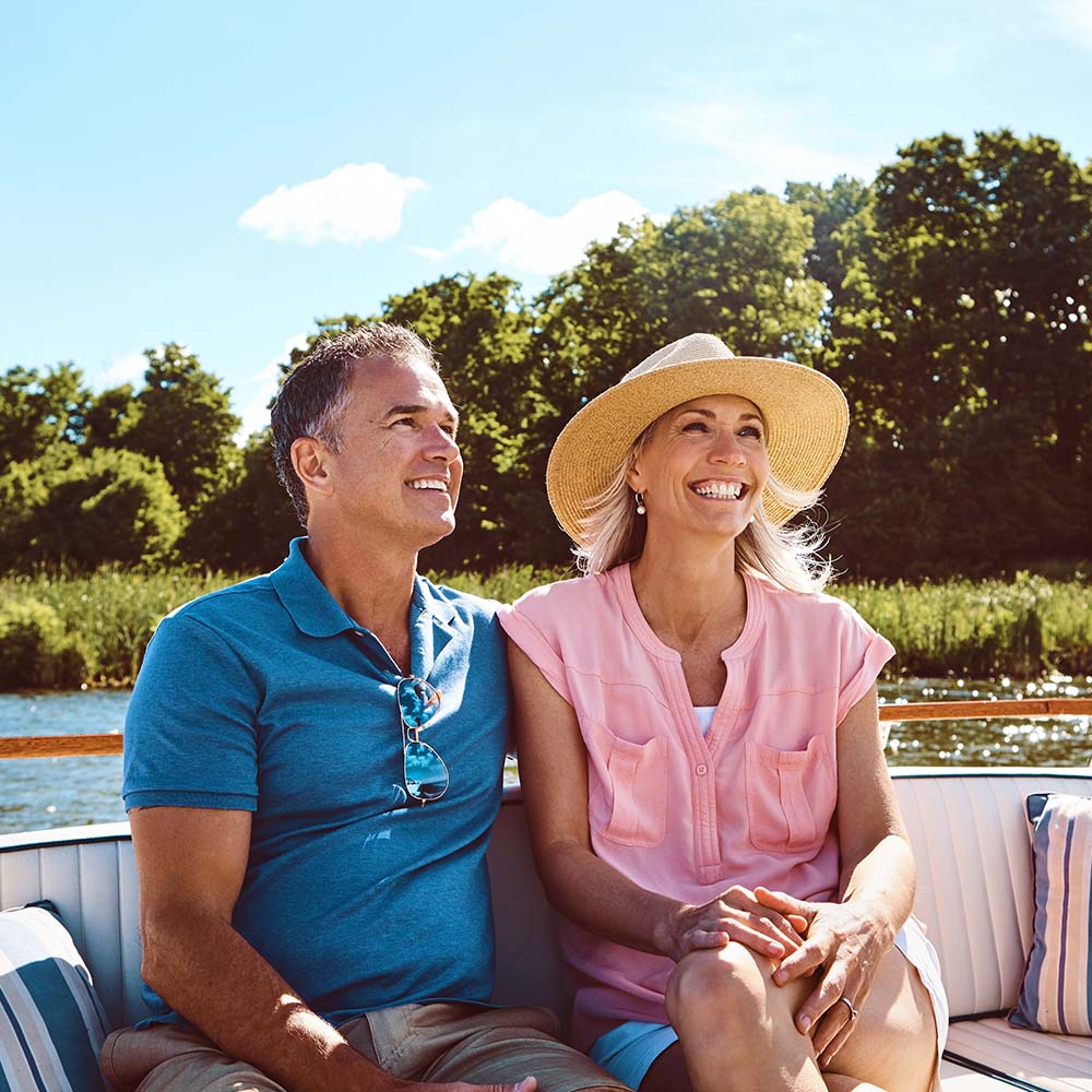 Middle aged couple sitting on a riverboat, smiling