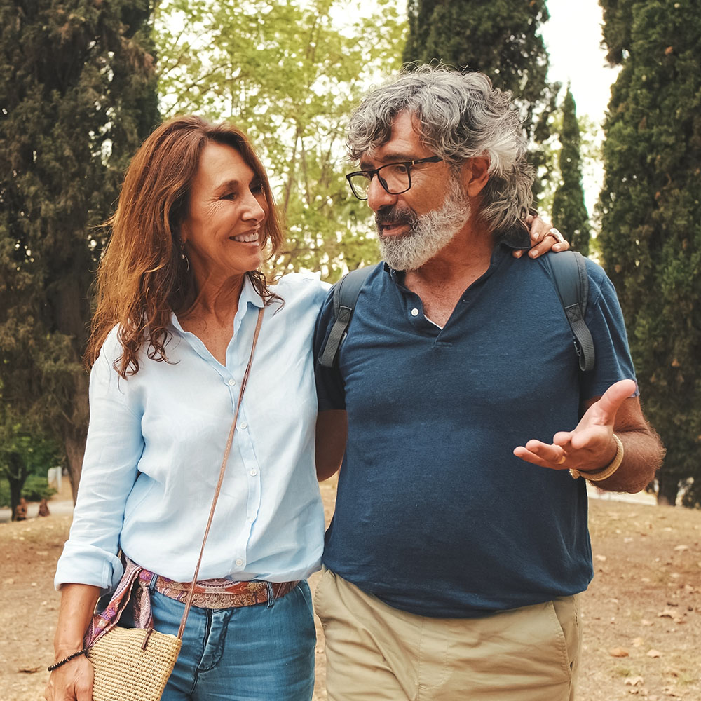 Mature couple walking in a park, talking and embracing each other.