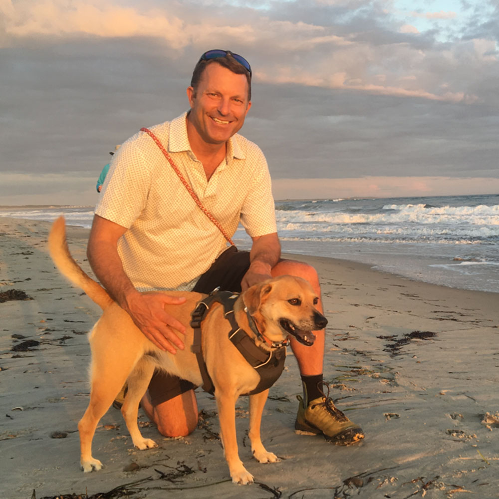 Image of Kurt Jamiel, founder of Income Associates with his dog on a beach.